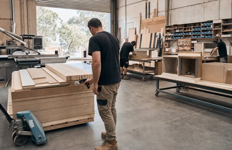 Joinery worker moving materials on a trolley in a manufacturing workshop